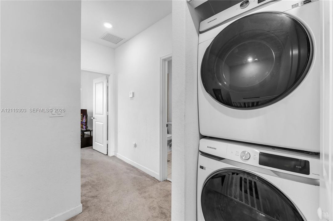 Built-in stacked laundry appliance, carpeted flooring, and recessed ceiling lighting
