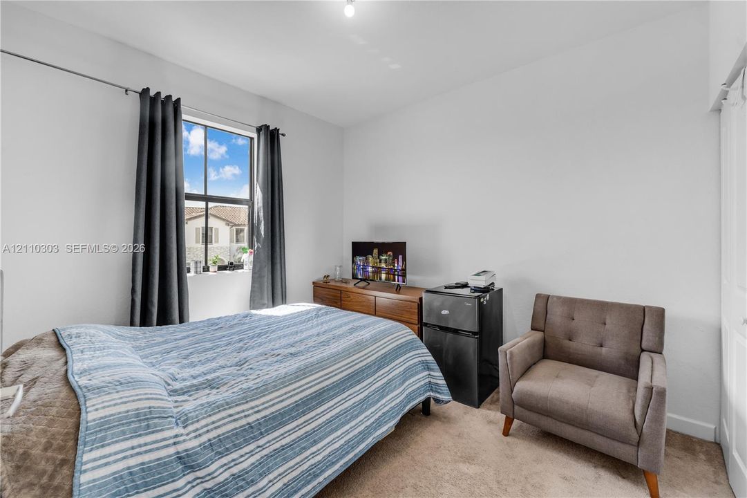 Bedroom featuring neutral wall paint, carpeting, a multi-pane window, and a closet with bifold doors