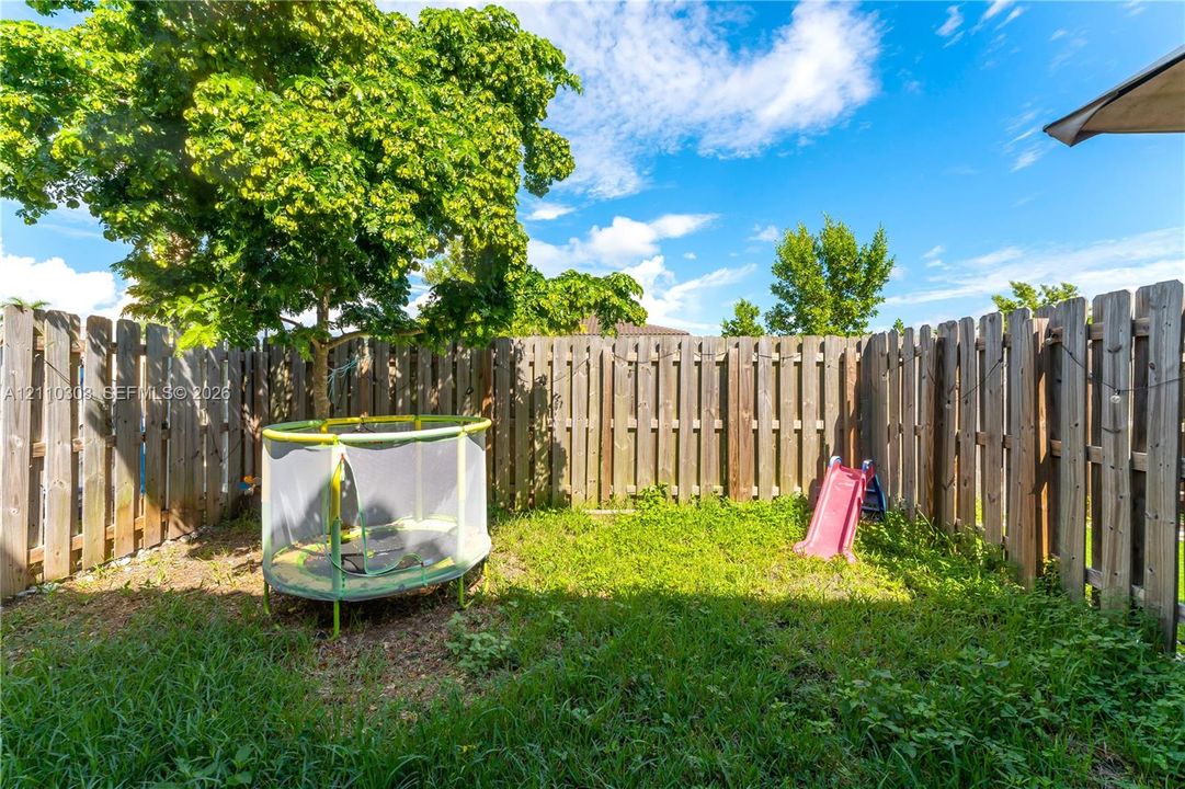 Fenced backyard featuring wood privacy fencing and a mature shade tree