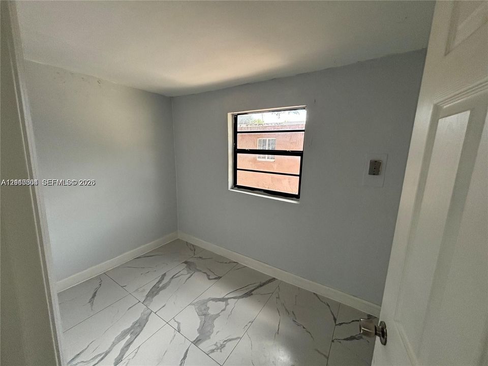 Interior space featuring large-format light-toned tile flooring with veining, neutral wall paint, and a single-pane horizontal sliding window