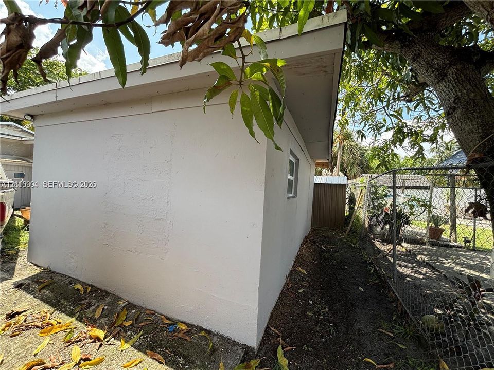 Stucco exterior with a pitched roofline and chain-link fencing