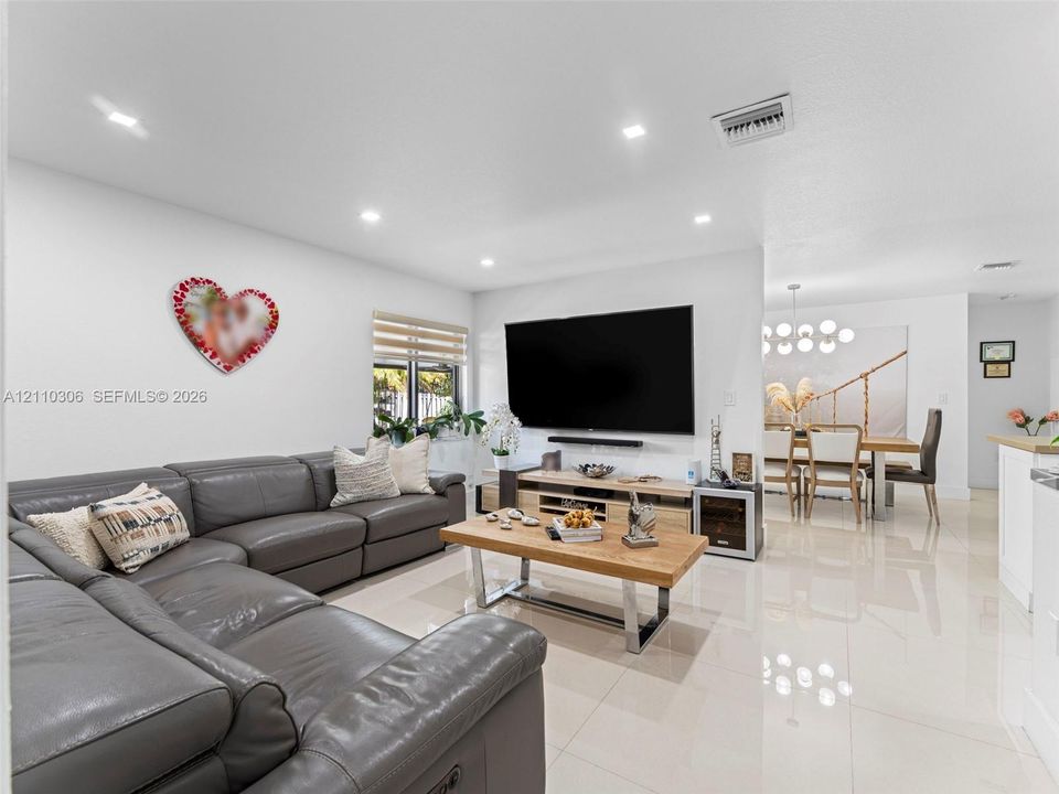 Open-concept interior featuring large-format tile flooring, recessed lighting, and dual-shade window treatments