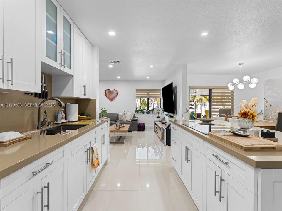 Kitchen featuring white shaker-style cabinetry, solid-surface countertops, recessed lighting, and large-format tile flooring