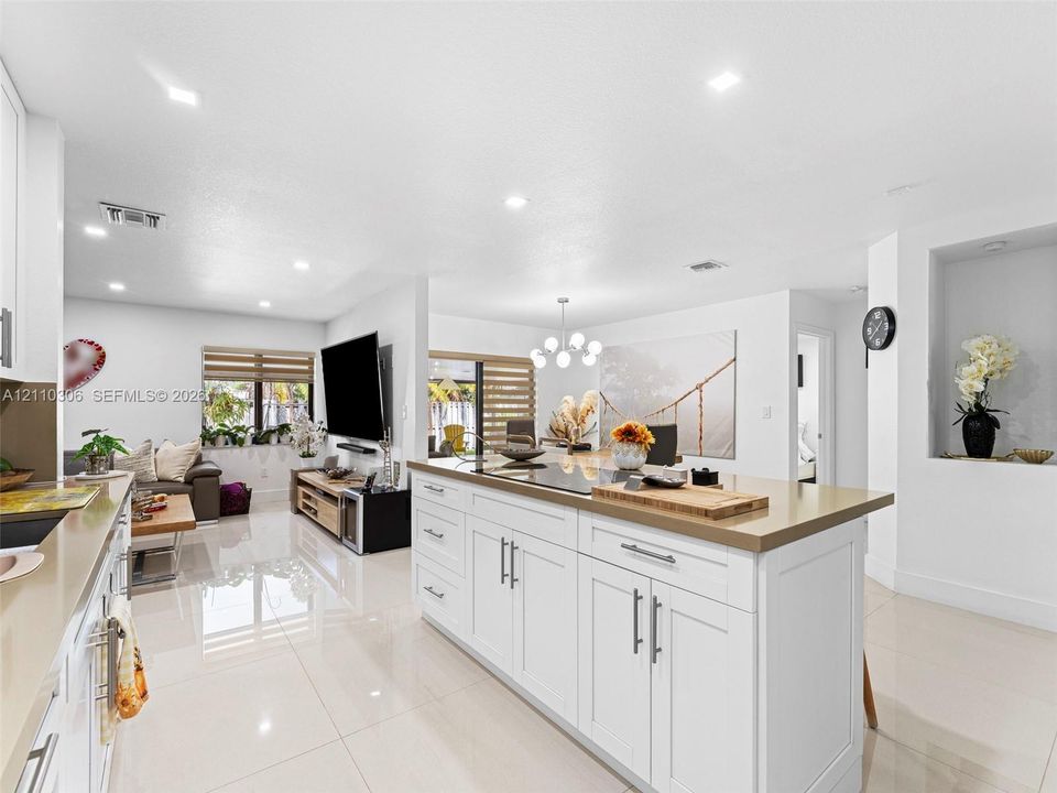 Kitchen featuring a large central island with white shaker-style cabinetry, solid-surface countertops, recessed lighting, and tile flooring