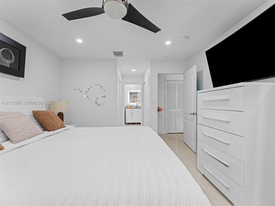 Neutral-toned interior featuring recessed lighting, a modern three-blade ceiling fan, smooth-surface tile flooring, and closet doors with louvered panel detailing