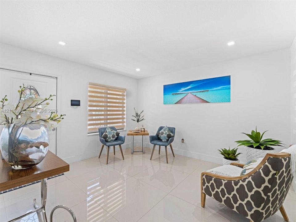 Light-filled room featuring large-format tile flooring, recessed ceiling lighting, and horizontal dual-shade blinds