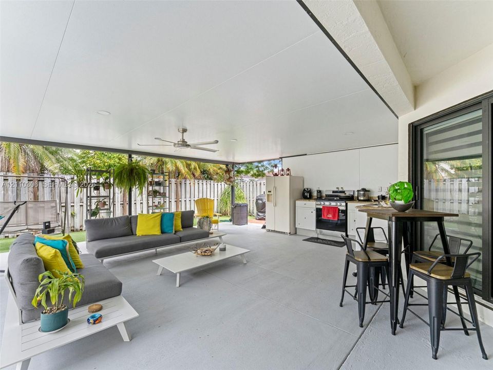 Covered patio featuring a painted concrete floor, ceiling fan, recessed lighting, and an outdoor kitchenette with white cabinetry