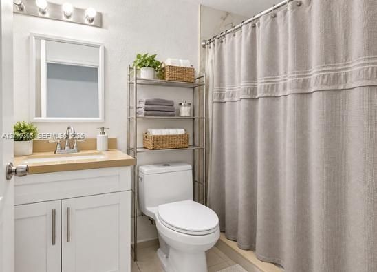 Bathroom featuring a white vanity cabinet, solid-surface countertop with an integrated sink, polished chrome faucet, framed wall mirror, and vanity lighting fixture