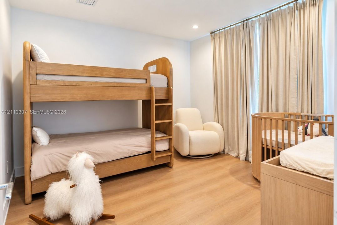 Bedroom featuring light wood-finish flooring, recessed lighting, and full-height neutral drapery