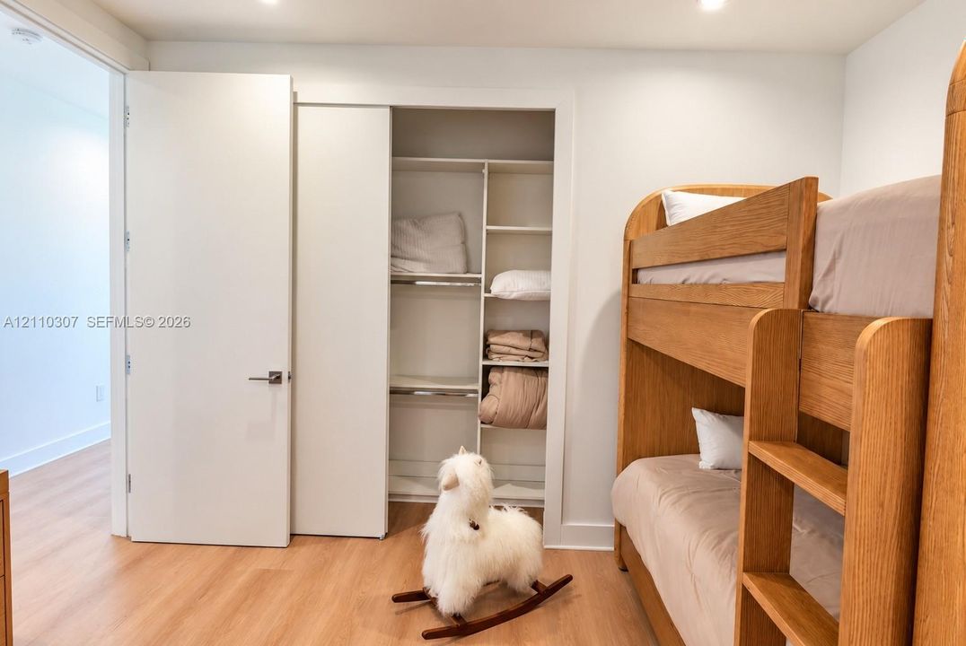 Interior room featuring wood-finish flooring, a built-in closet with multi-tier shelving, and a solid-core swing door with matte-finish hardware