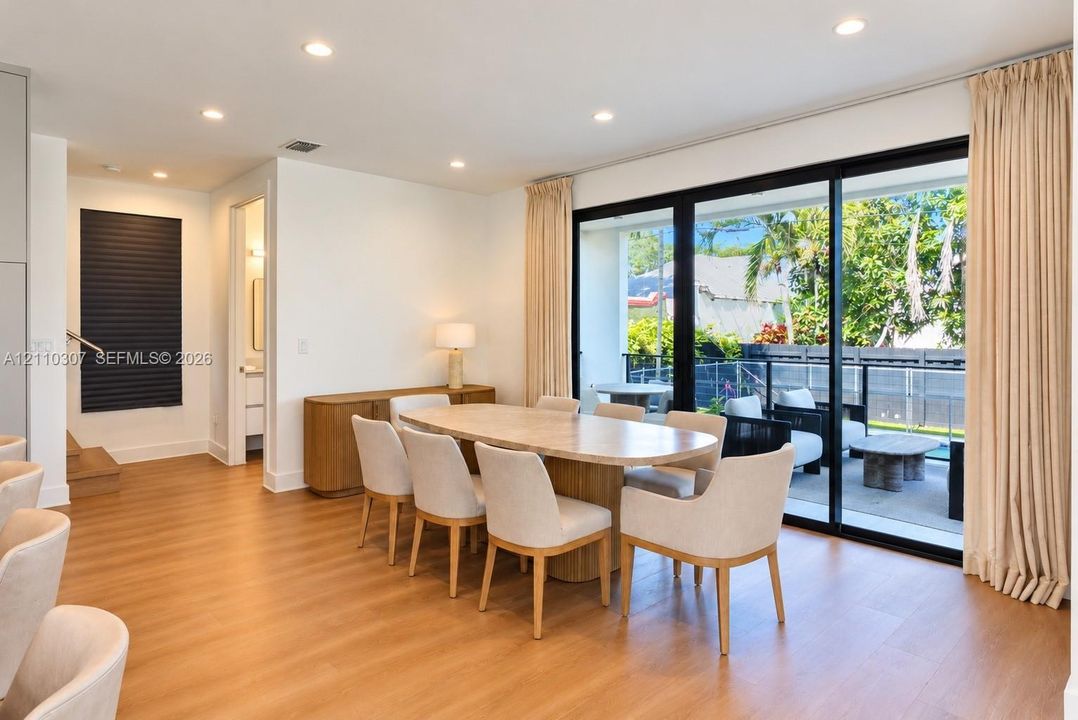 Wood-finish flooring, recessed lighting, and floor-to-ceiling sliding glass doors opening to a balcony