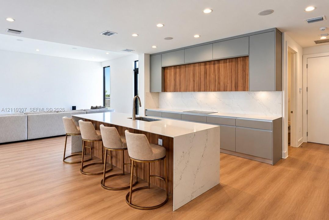Kitchen featuring a waterfall-edge island with stone-finish countertops, wood-finish cabinetry, built-in cooktop, and recessed lighting