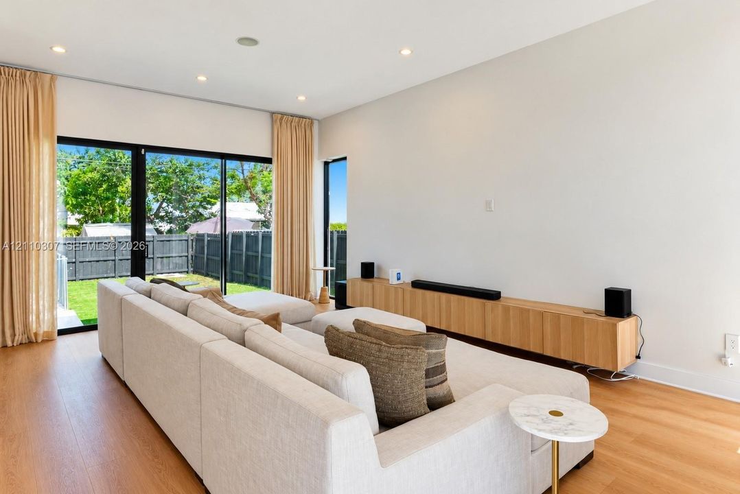 Living area featuring wood-finish flooring, recessed lighting, and large sliding glass doors providing outdoor access