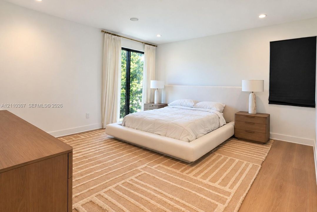 Bedroom featuring wide-plank wood-finish flooring, recessed lighting, and a floor-to-ceiling glass sliding door with exterior access