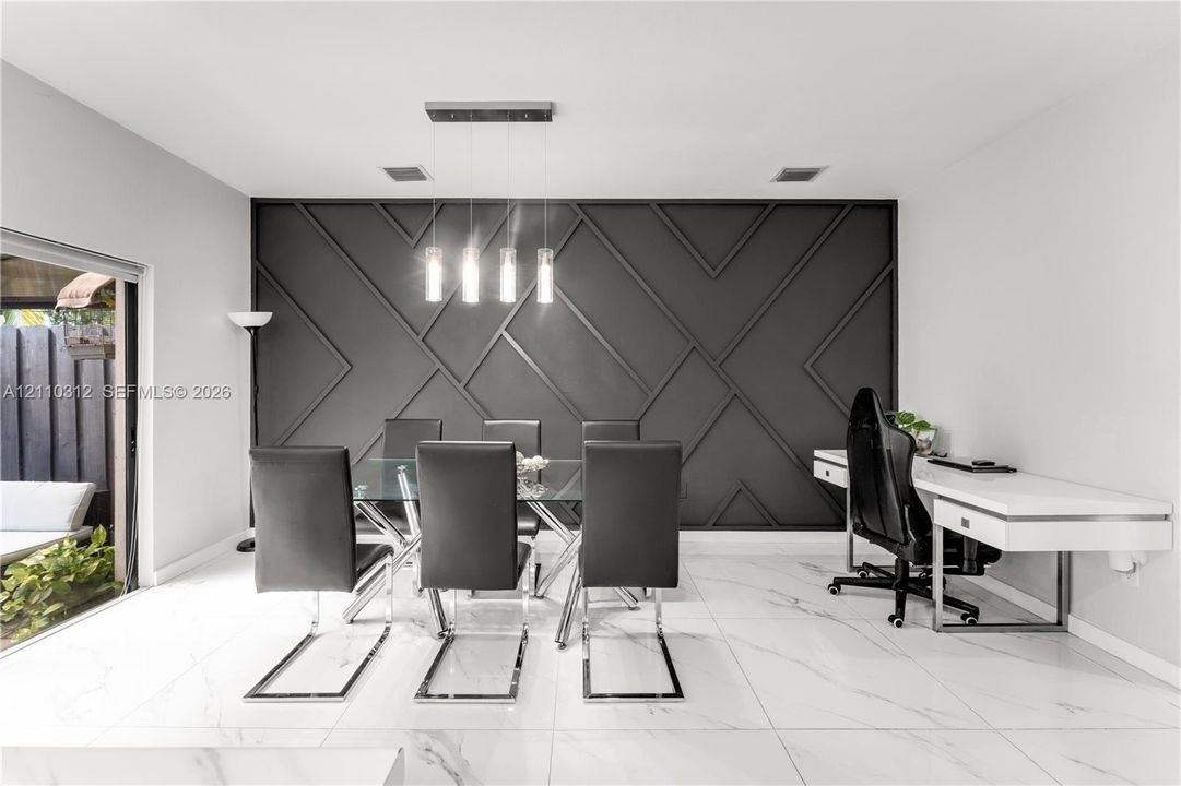 Geometric accent wall with matte black finish, large-format tile flooring, and four-light linear pendant fixture