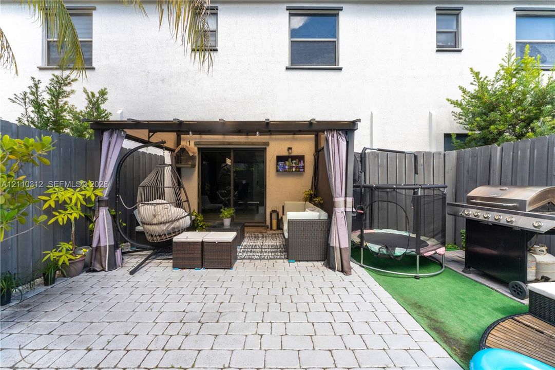 Private patio featuring interlocking concrete pavers, a built-in pergola structure, and a full-perimeter privacy fence