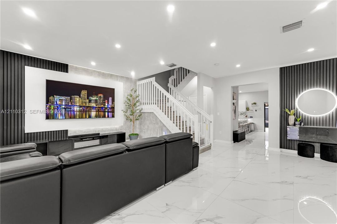 Living area featuring large-format tile flooring, recessed ceiling lighting, vertical slat wall paneling, and a staircase with white wood railings