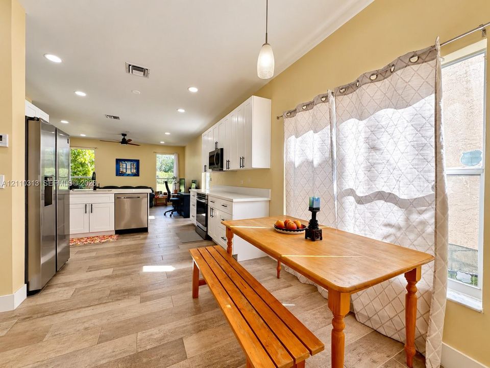 Kitchen featuring white shaker-style cabinetry, stainless steel appliances, wood-finish tile flooring, recessed lighting, and a pendant light fixture