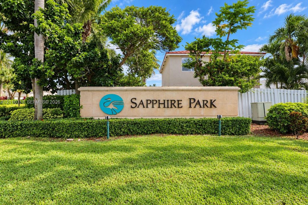 Community entrance monument featuring a stone-clad wall, dimensional lettering, professional landscaping, and manicured turf