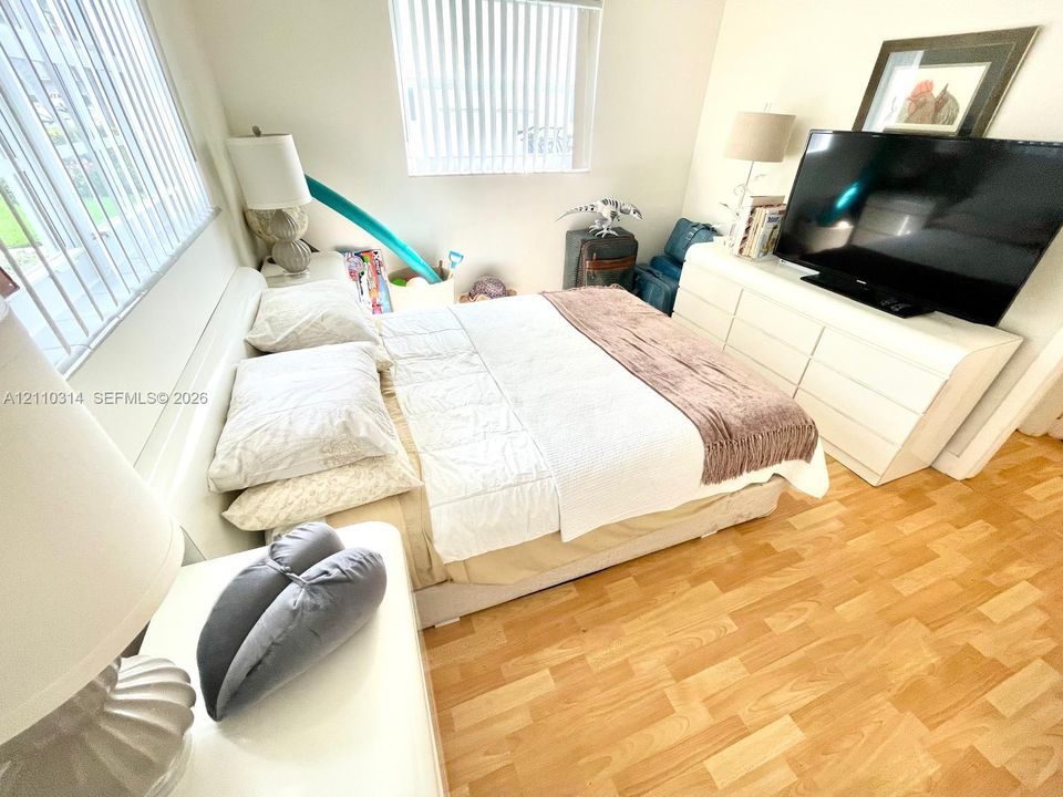 Wood-finish flooring and dual windows featuring vertical blinds
