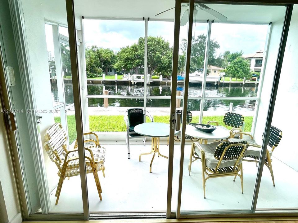 Screened-in patio featuring concrete flooring, ceiling fan, and direct water frontage with a bulkhead