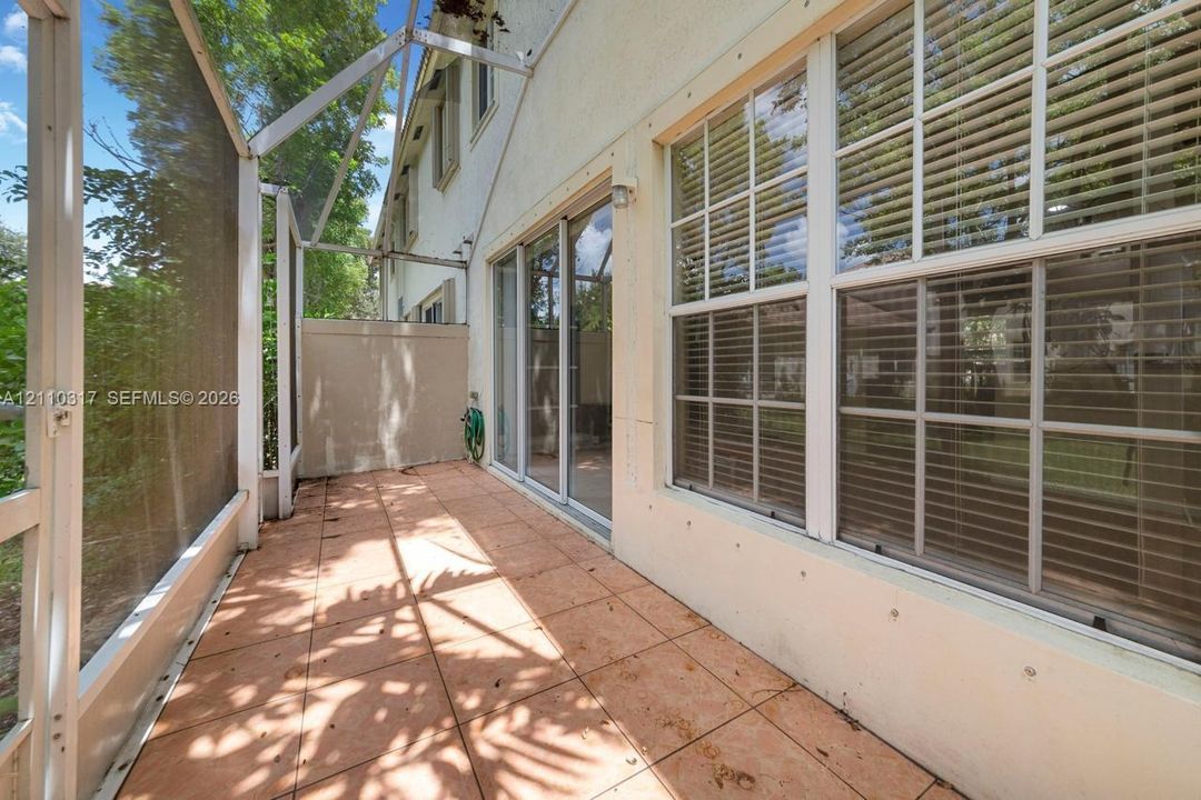 Enclosed lanai featuring screen panels, tiled flooring, glass sliding doors, and multi-pane windows with horizontal blinds