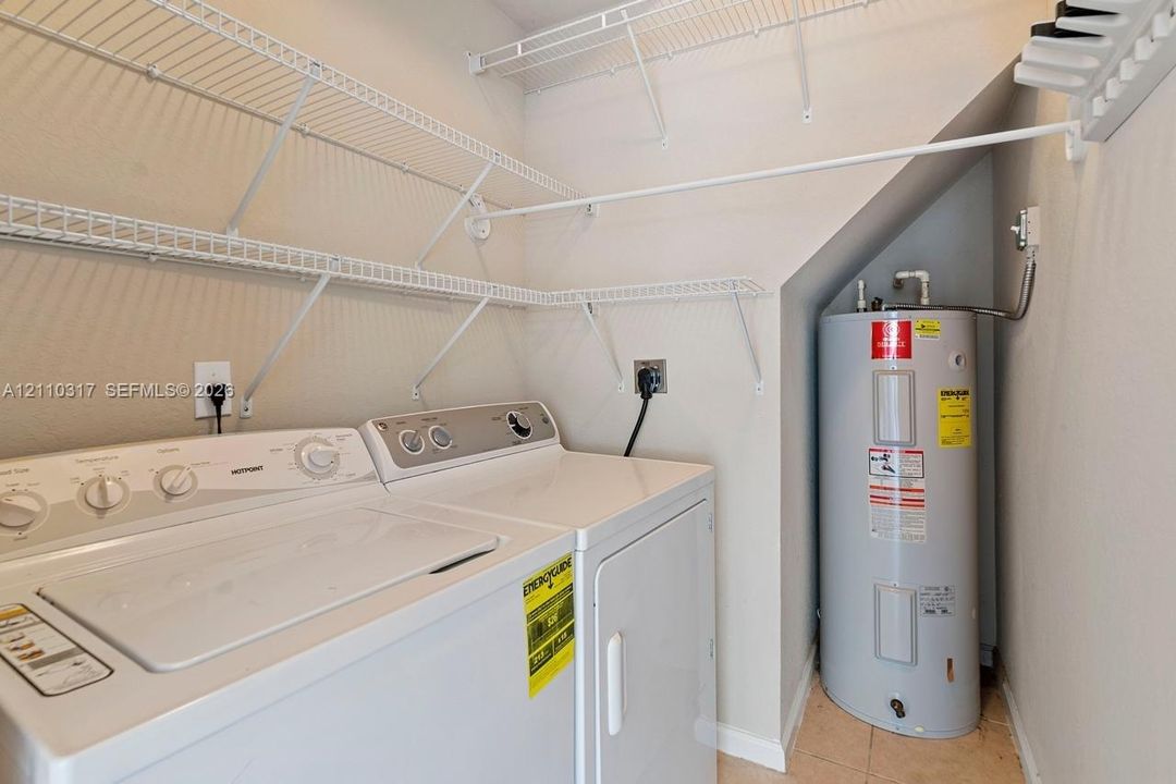 Utility space featuring built-in wire shelving and a floor-mounted water heater