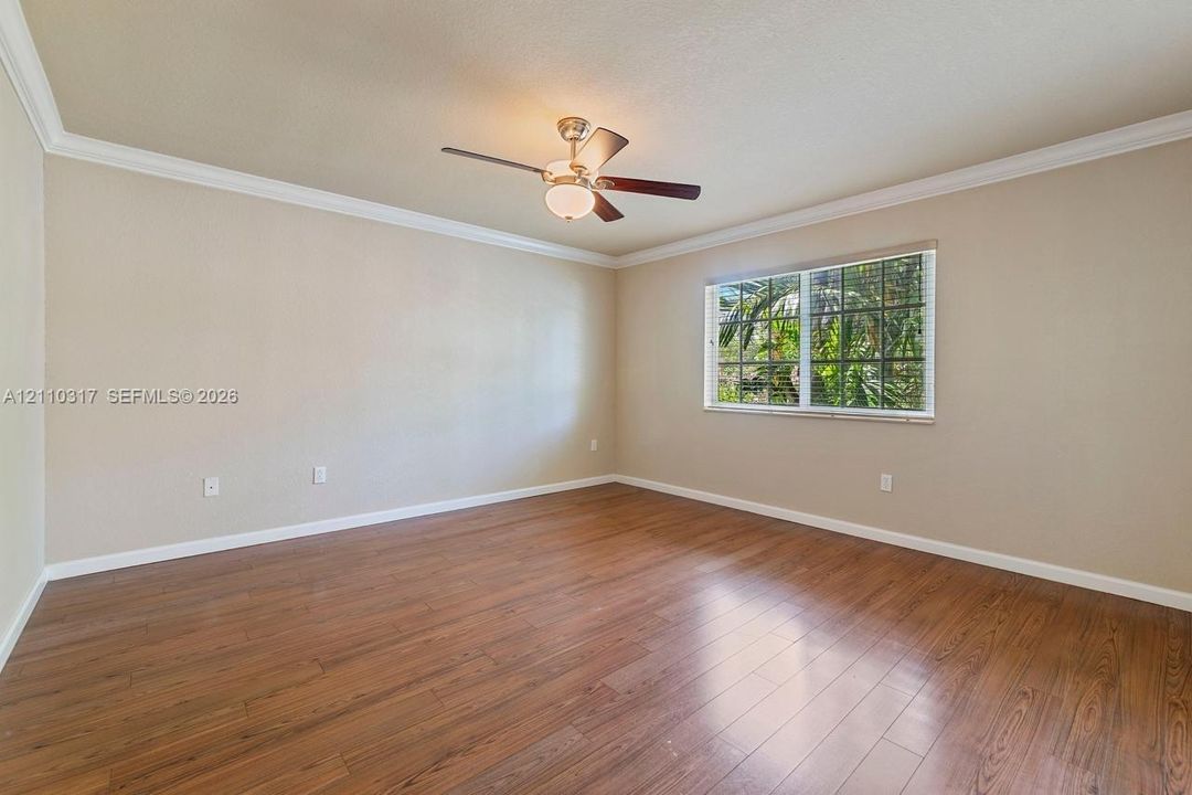 Room featuring wood-finish flooring, crown molding, and a ceiling fan with integrated lighting