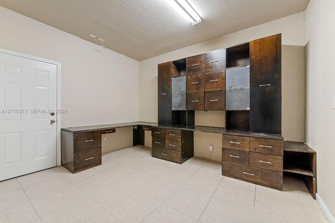 Built-in wooden cabinetry featuring extensive drawer storage, open shelving, and metal hardware, complemented by tile flooring and a flush-mount linear light fixture