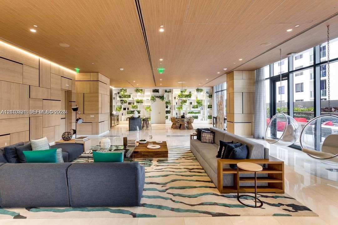 Expansive room featuring a wood-paneled ceiling, floor-to-ceiling glass wall, built-in recessed wall cladding, stone flooring, and integrated display shelving