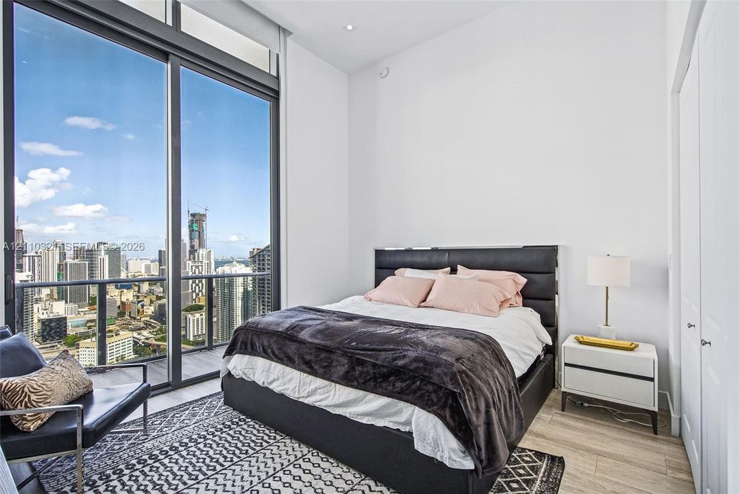 Floor-to-ceiling windows, wood-finish flooring, recessed lighting, and a glass-paneled balcony railing