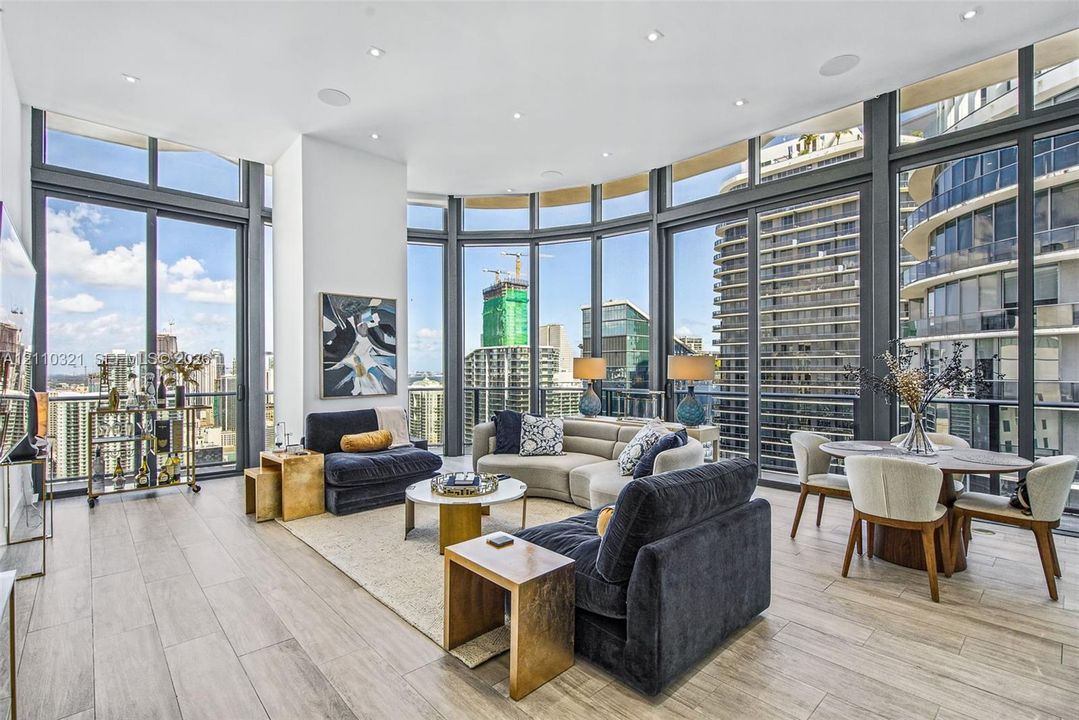 Floor-to-ceiling windows with expansive urban outlooks, wood-finish flooring, and recessed ceiling lighting
