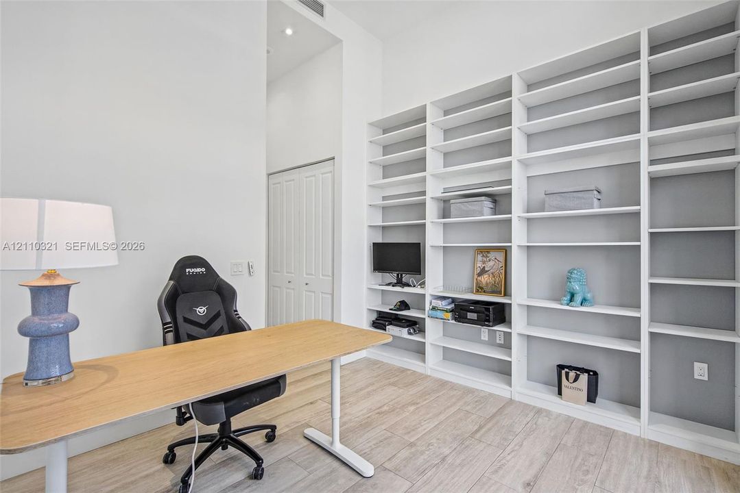 Floor-to-ceiling built-in white shelving, wood-finish flooring, and high ceilings