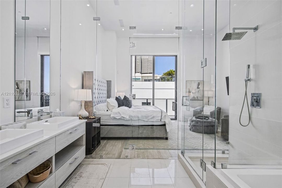 Dual vanity with rectangular vessel sinks, floor-to-ceiling glass-enclosed shower, polished stone flooring, and recessed ceiling lighting