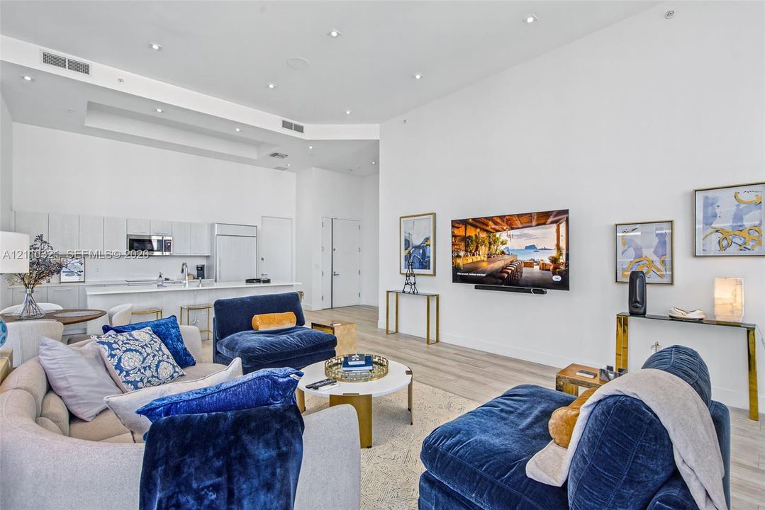 Open-concept interior featuring high ceilings with recessed lighting, light wood-finish flooring, and a kitchen equipped with flat-panel cabinetry and an eat-in peninsula
