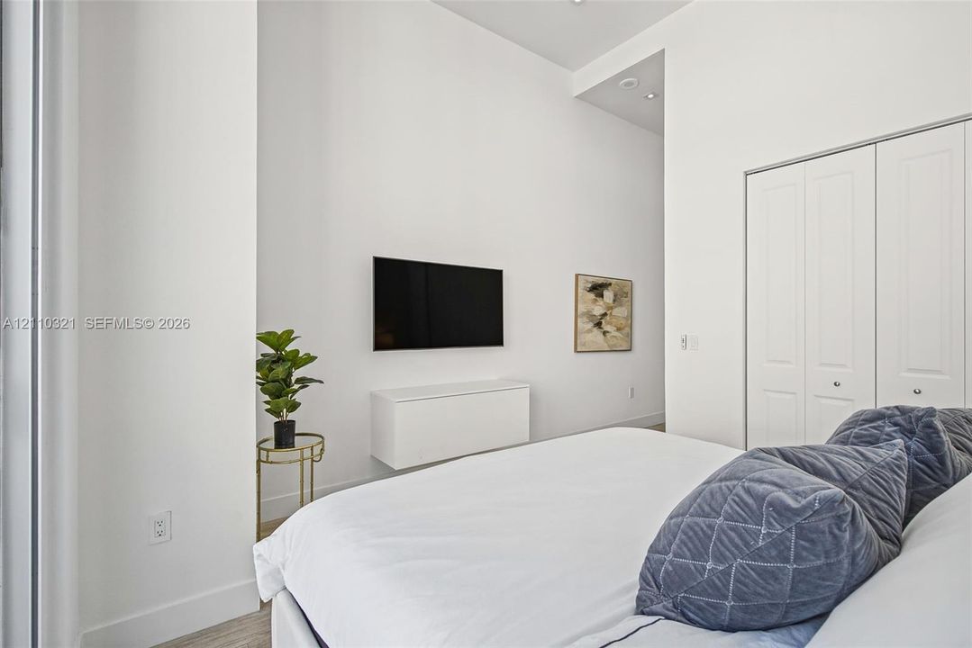 High ceilings, white walls, wood-finish flooring, recessed lighting, and white bi-fold closet doors