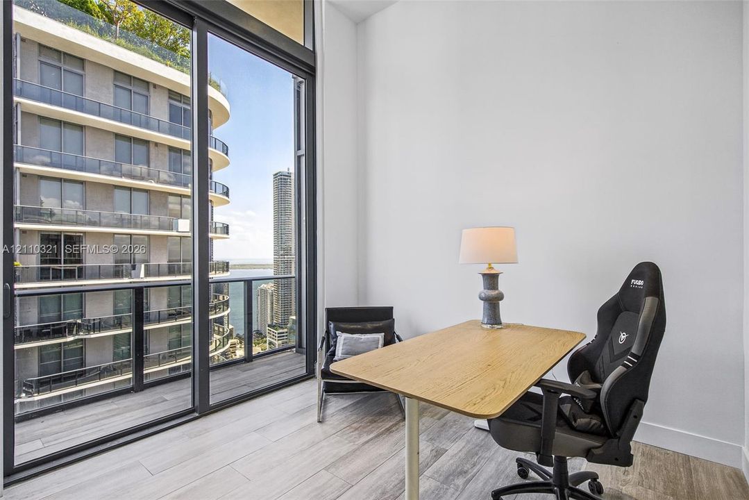 Floor-to-ceiling sliding glass panels, wood-finish flooring, and a private balcony with glass railing