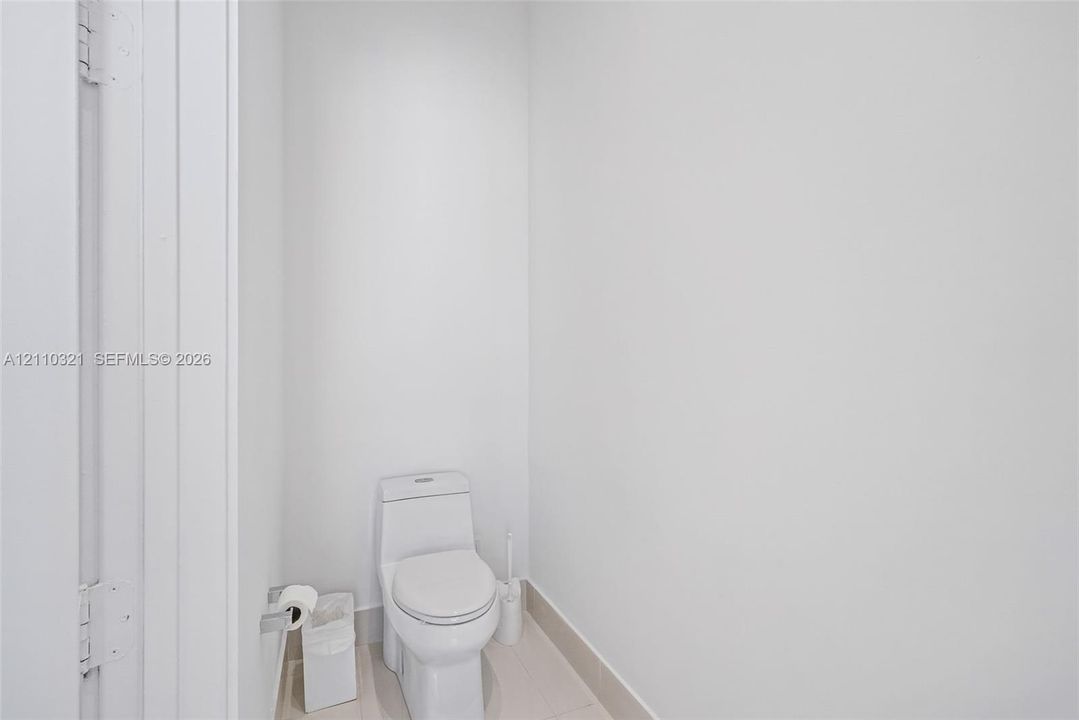 One-piece dual-flush toilet featuring a sleek, skirted base and neutral tile flooring