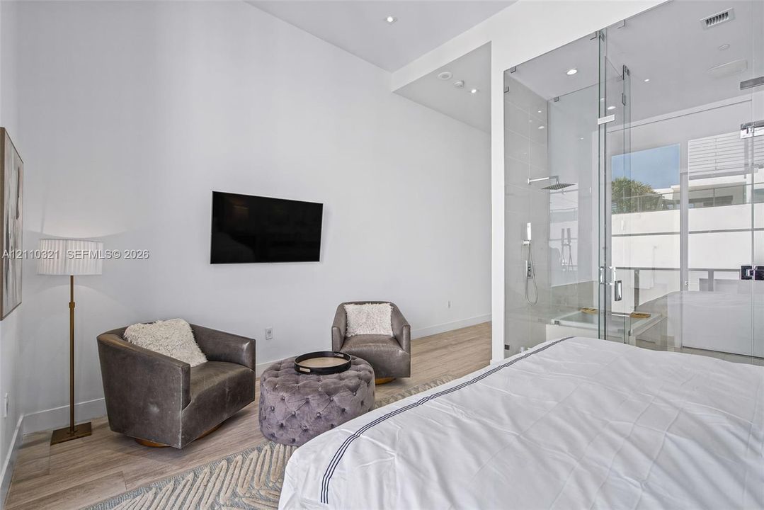 High ceilings, wood-finish flooring, and floor-to-ceiling glass-enclosed shower featuring a rainfall showerhead
