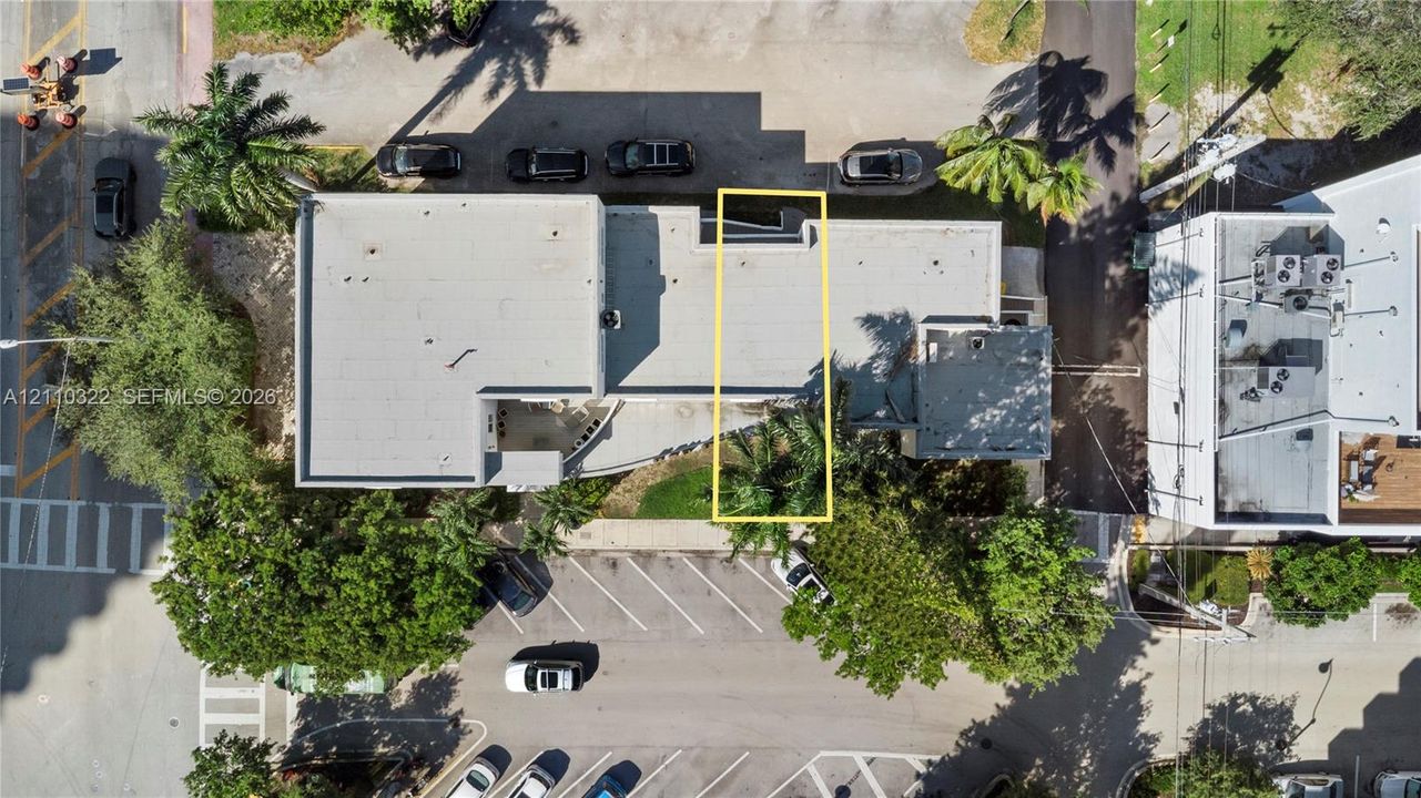 Aerial perspective featuring a flat-roof structure with designated surface parking