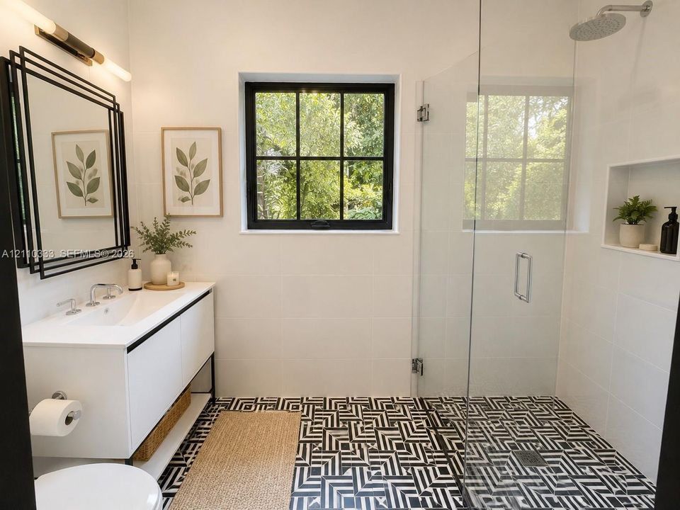 Bathroom featuring a white vanity with an integrated sink, geometric tile flooring, a glass-enclosed shower with a rainfall showerhead, and a multi-frame wall mirror