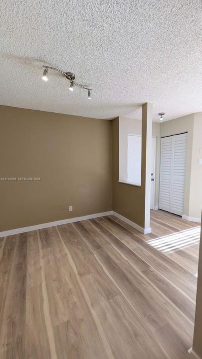 Wood-finish flooring, tri-light track lighting, and louvered closet doors