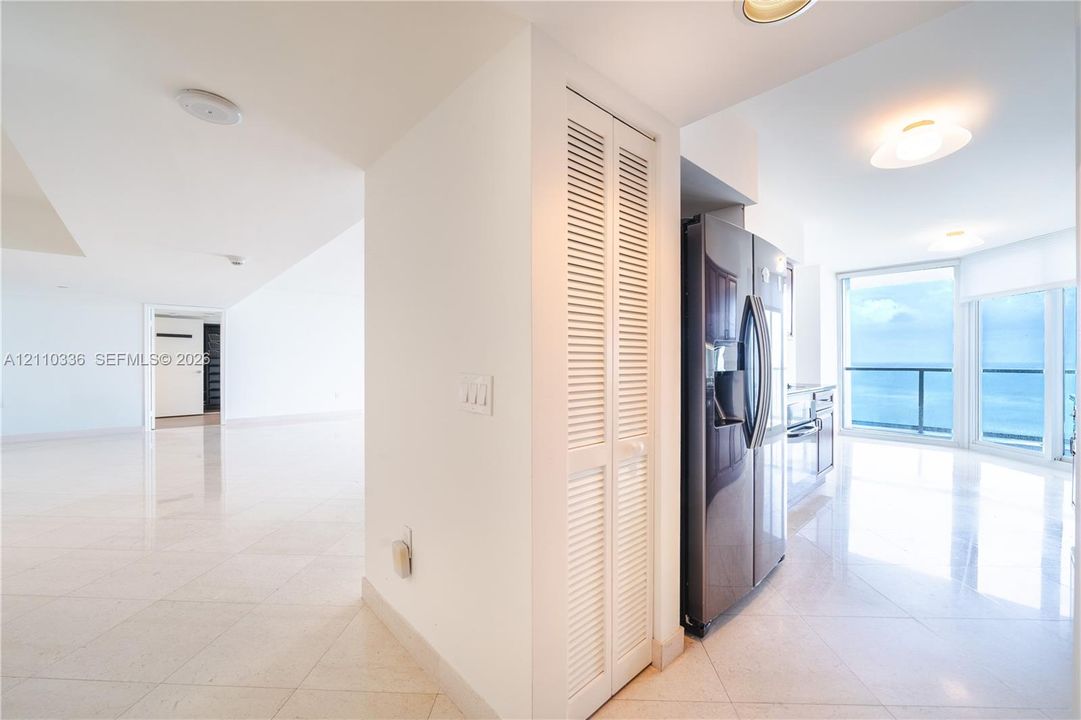 Interior space featuring polished stone flooring, recessed lighting, white louvered closet doors, stainless steel refrigerator, and floor-to-ceiling windows