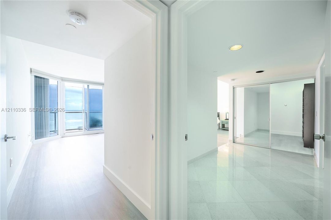 Floor-to-ceiling glass sliding doors, private balcony, large-format tile flooring, and mirrored sliding closet doors