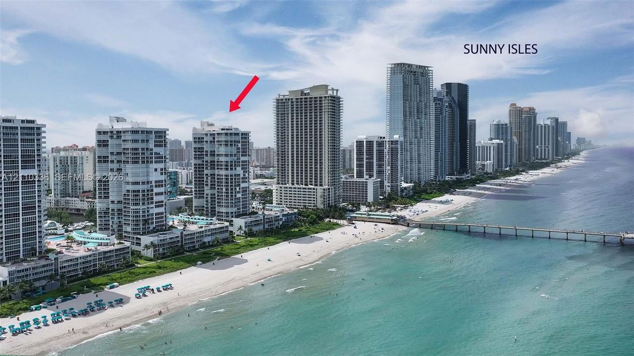Aerial perspective of Sunny Isles coastal high-rise building with direct oceanfront proximity