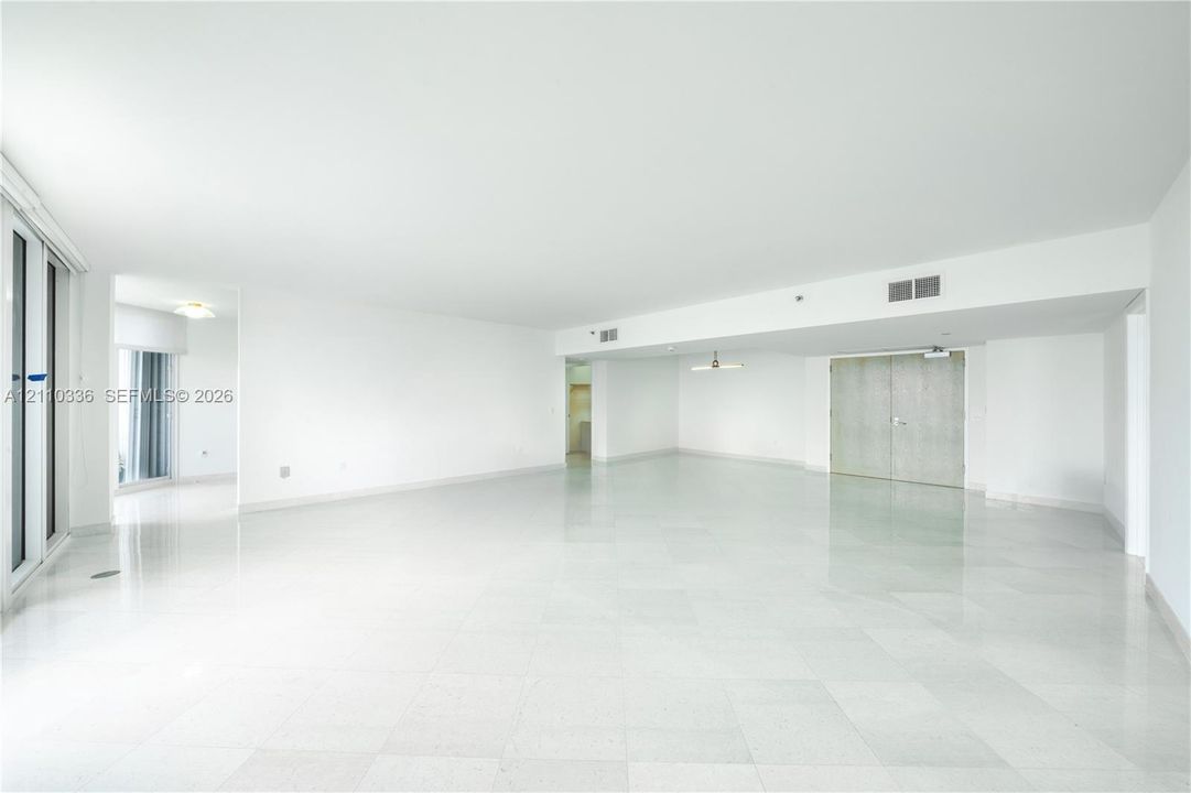 Open-concept interior featuring polished tile flooring, smooth ceilings, recessed lighting, and double-door closet entry