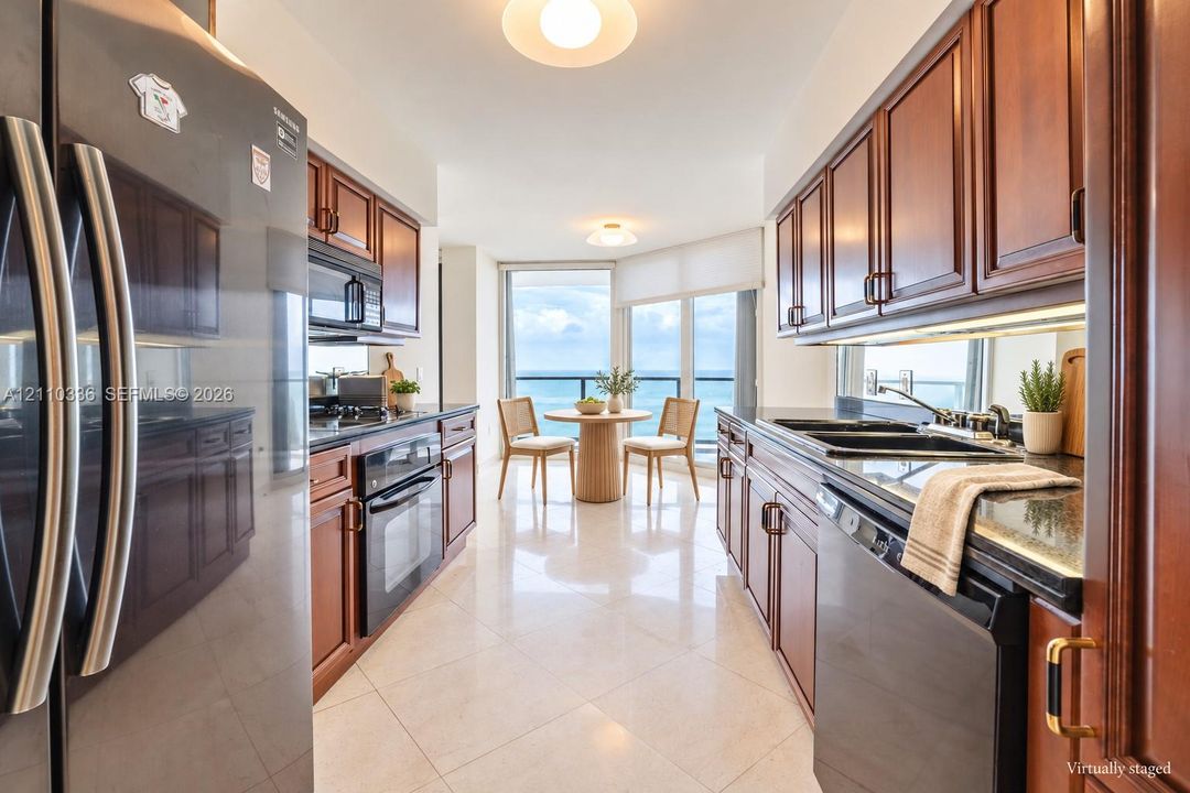 Galley kitchen featuring rich wood cabinetry, stone countertops, stainless steel appliances, and large-format tile flooring, complemented by expansive floor-to-ceiling windows