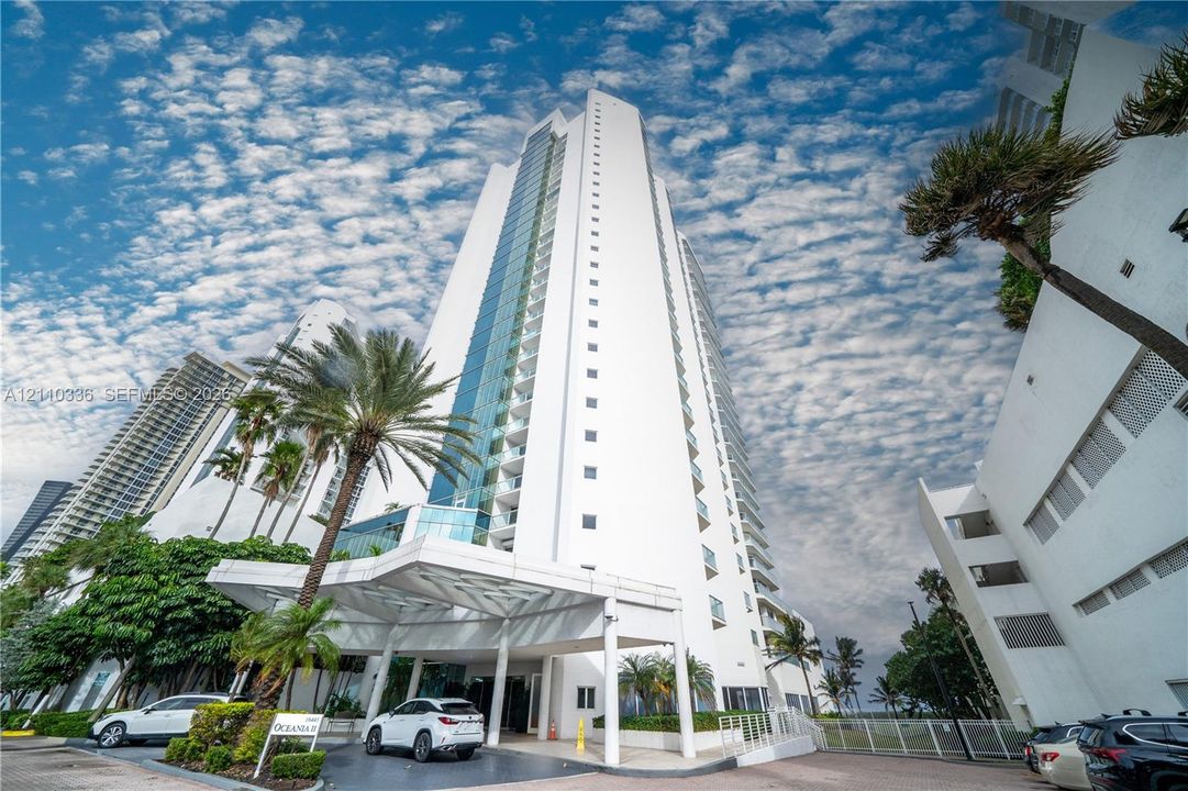 High-rise residential tower featuring a glass-paneled facade, private balconies, and a porte-cochère entry with structural columns
