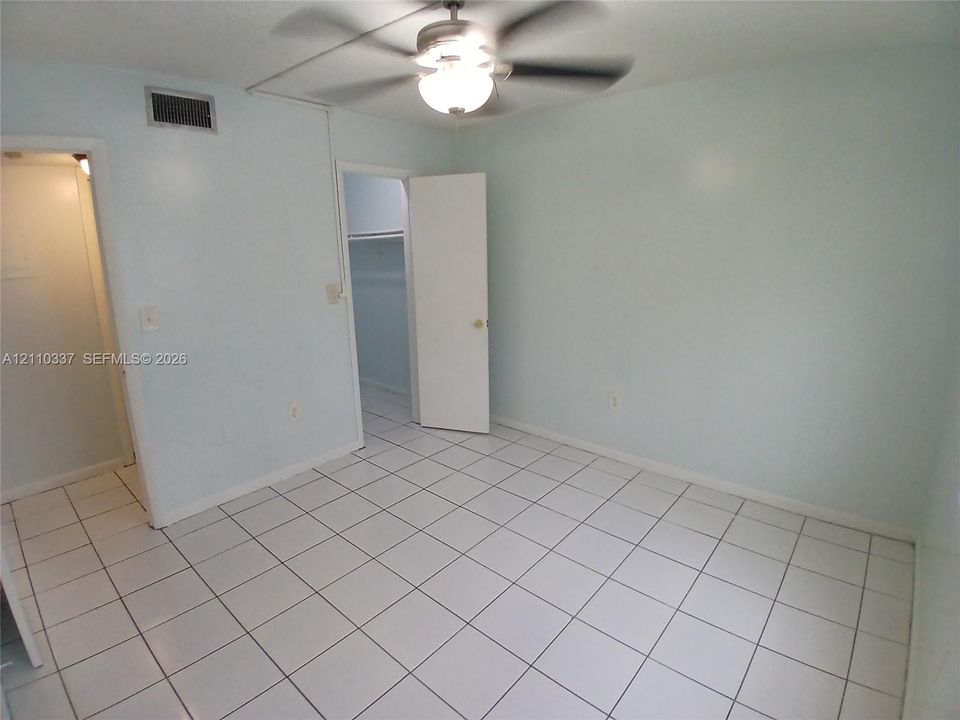 Ceramic tile flooring, ceiling fan with integrated light fixture, and closet with built-in shelving