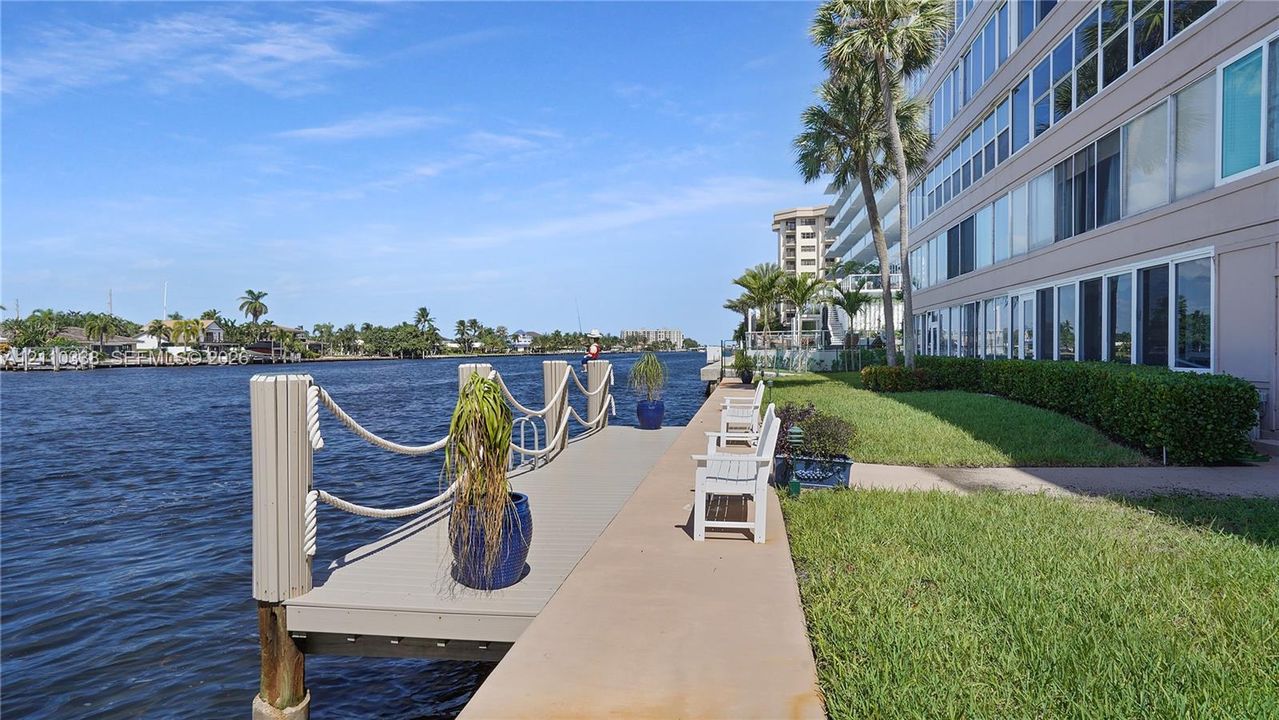 Waterfront dock with rope railing, concrete seawall, and manicured landscaping